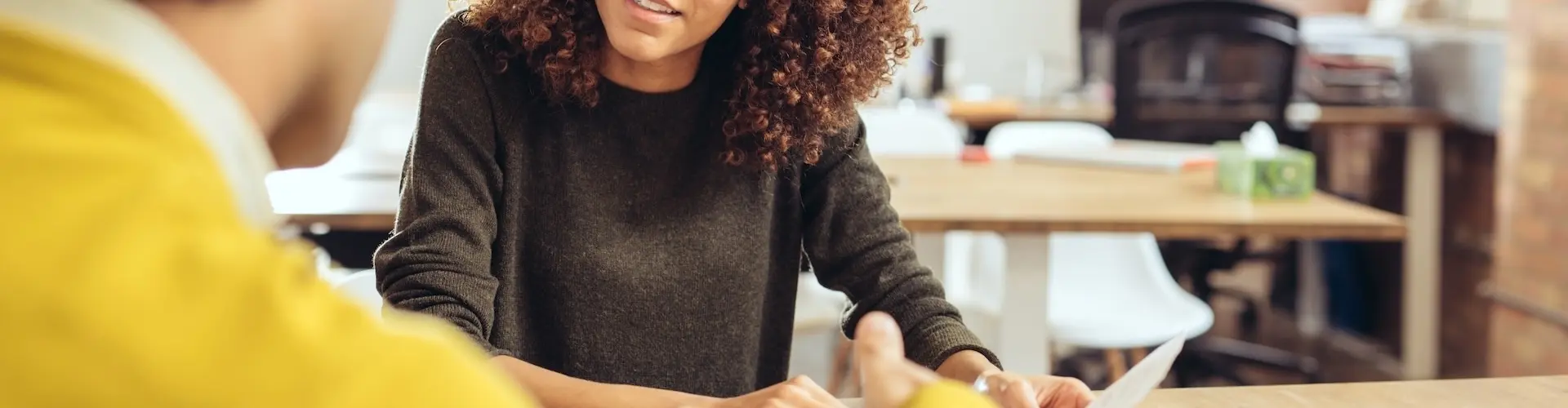 Lady in glasses talking to a man in a yellow jumper