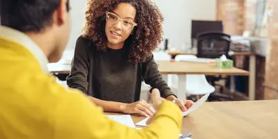 Lady in glasses talking to a man in a yellow jumper