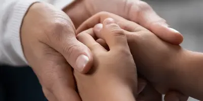 Two pairs of hands clasping together